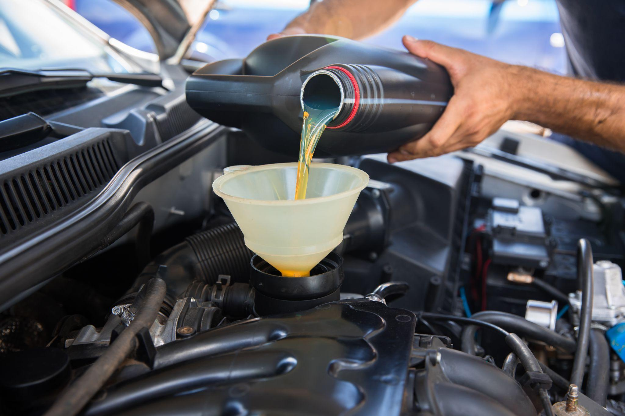 Mechanic pouring engine oil into vehicle